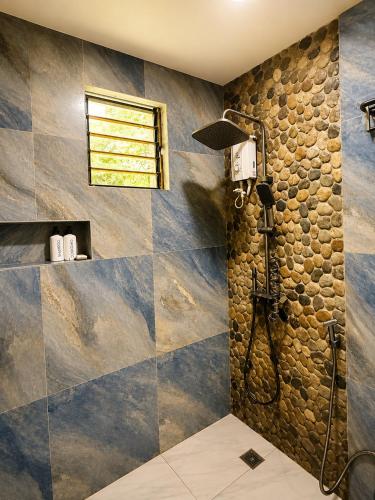 a bathroom with a shower with a stone wall at R&C Transient House in El Nido