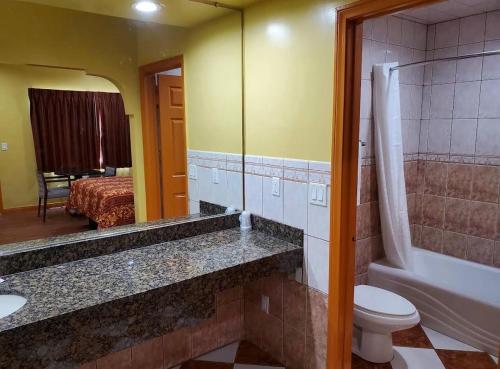 a bathroom with a toilet and a sink and a mirror at Sunrise Inn in South Gate
