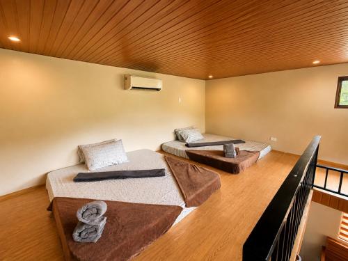 two beds in a room with a wooden ceiling at R&C Transient House in El Nido
