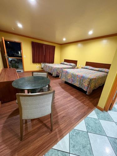 a hotel room with two beds and a table at Sunrise Inn in South Gate