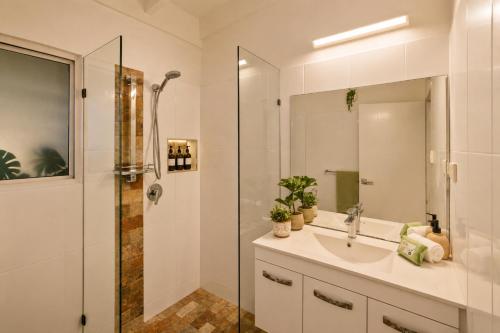 a white bathroom with a sink and a shower at Cairns Beachfront Retreat in East Trinity