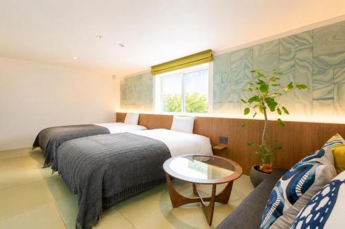 a hotel room with two beds and a table at Nagi Kurashiki Hotel&Lounge in Kurashiki