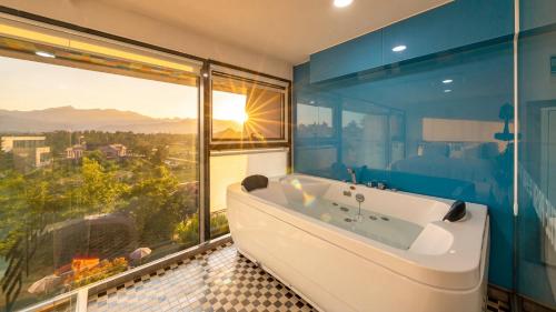 a bathroom with a tub and a large window at goseong theprism pension in Goseong