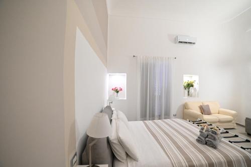 a white bedroom with a bed and a chair at Maris Terra in Brindisi