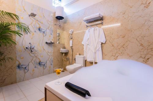 a bathroom with a white bed and a glass of wine at Next-stay in Udaipur