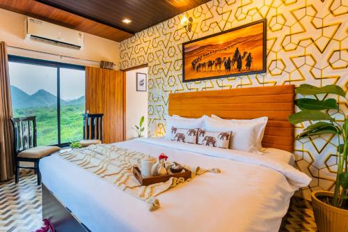 a bedroom with a large white bed with a large window at Next-stay in Udaipur