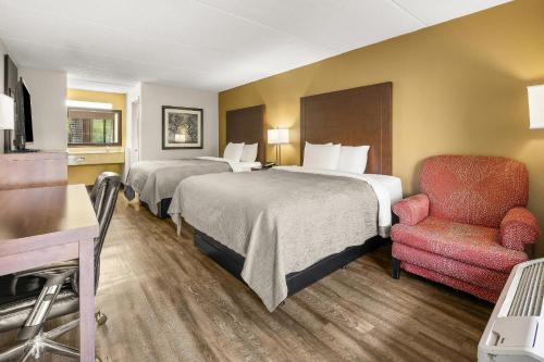 a hotel room with two beds and a chair at Quality Inn Columbus near Fort Benning in Columbus