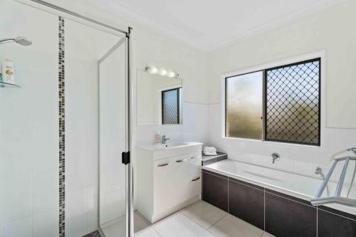 a bathroom with a tub and a sink and a shower at The Seahaven - Modern 5 Bedroom Family Home Close to Beach in Pialba