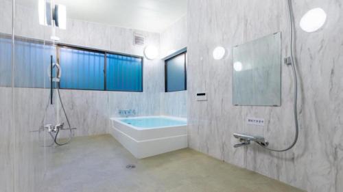 a bathroom with a tub and a sink and a mirror at rinne 2nd living Sauna Villa Nasu in Nasu