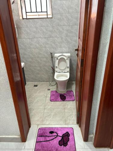 a bathroom with a toilet with purple mats on the floor at Relaxing Lodge in Kigali