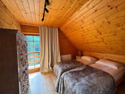 a bedroom with two beds in a wooden cabin at Przystanek Beskidy in Brenna