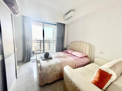 a bedroom with a bed and a couch and a window at U Mall Condo in Sihanoukville