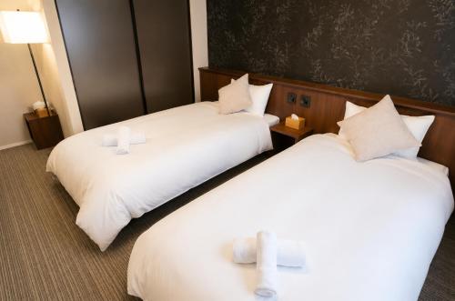 two beds in a hotel room with candles on them at SOULEIADO Shinosaka in Osaka