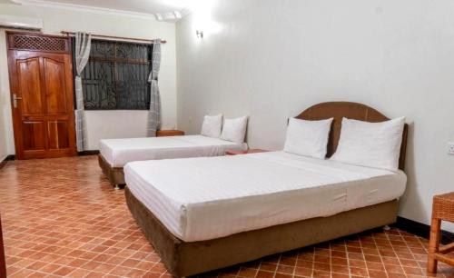 a bedroom with two beds and a door at Paradiso Hotel in Dar es Salaam