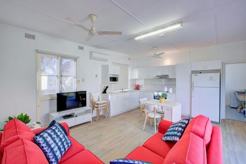a living room with a red couch and a kitchen at Ruby in Exmouth