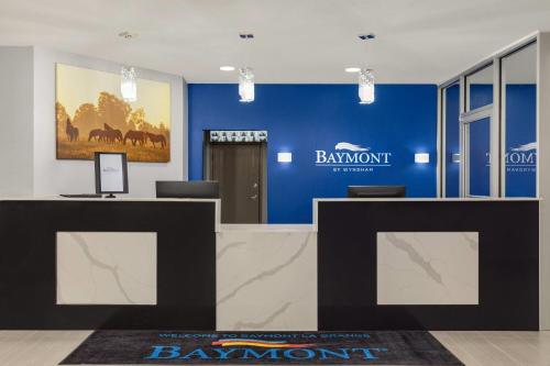a lobby with a blue wall with a sign on it at Baymont by Wyndham La Grange KY Southeast in La Grange