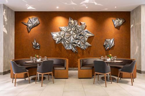 a dining room with two tables and chairs and artwork at Ramada Encore Istanbul Bayrampasa in Istanbul