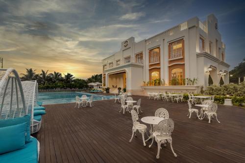 a patio with tables and chairs next to a pool at Miros, Goa in Old Goa