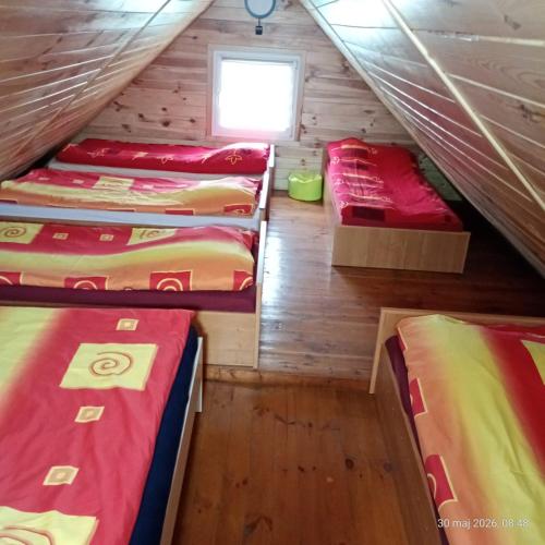 a attic room with four beds and a window at domek letniskowy Agroturystyka Sajkiewicz in Chmielnik