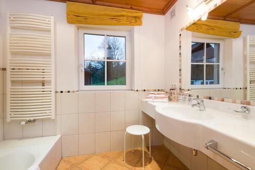 a bathroom with two sinks and two windows at Landhaus Alpensonne in Schattwald