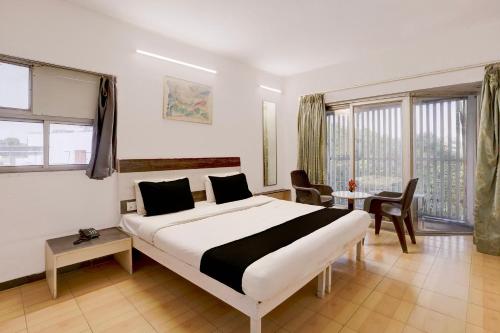a hotel room with a large bed and a table at Hotel O Bhavnagar Bus Terminal Formerly Jubliee in Bhavnagar