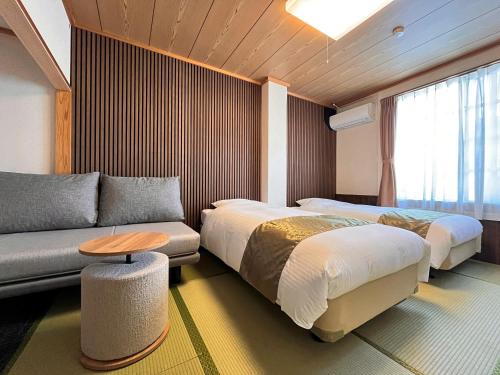 a hotel room with two beds and a couch at Hotel Cerulean Alpine in Otari