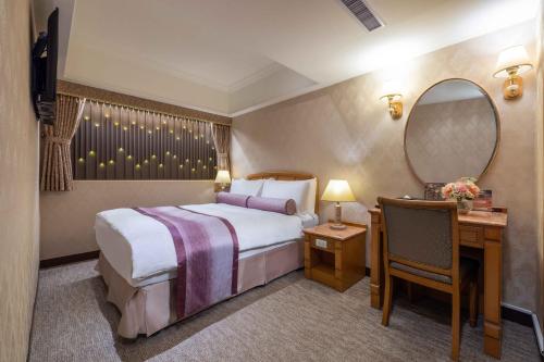 a hotel room with a bed and a desk and a mirror at Cosmos Hotel Taipei in Taipei