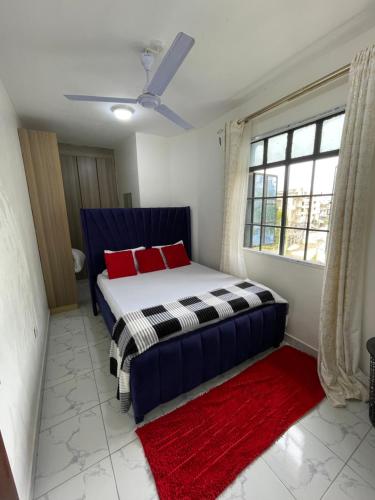 a bedroom with a bed with red pillows and a window at cozy 1bedroom mombasa bamburi near the beach with hot shower, Netflix, Secured parking 07&07 for 95 then 61to18 in Mombasa