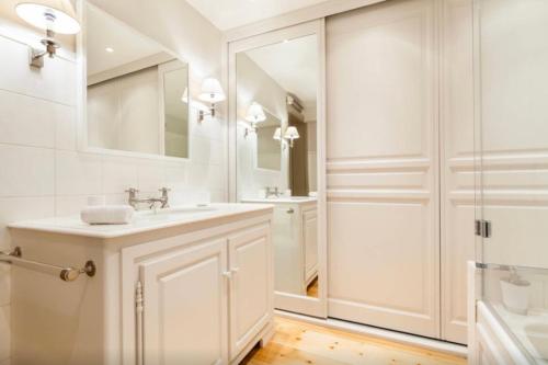 une salle de bain blanche avec un lavabo et un miroir dans l'établissement 1 Square du Docteur Blanche - Paris 16, à Paris