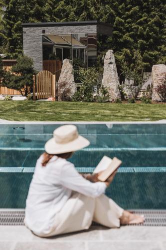 a woman sitting on the ground reading a book at Hotel Gaspingerhof in Gerlos