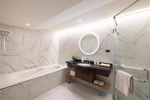 a bathroom with a tub and a sink and a mirror at Taoyuan Yuehua Hotel & Golf Club in Longtan
