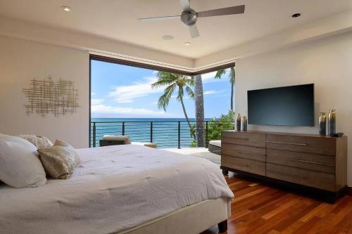 a bedroom with a bed and a large window with a television at Magnificent Oceanfront West Maui in Lahaina