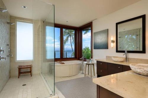 a bathroom with a shower and a tub and a sink at Magnificent Oceanfront West Maui in Lahaina