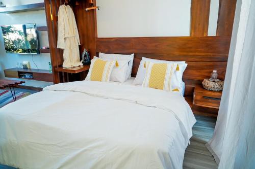 a bedroom with a white bed with a wooden headboard at Geza Breeze Residence in Kigamboni