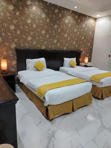 two beds in a hotel room with yellow sheets at اصيل الفاخره المخدومه in Taif