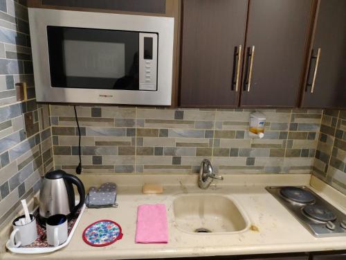 a kitchen counter with a microwave above a sink at اصيل الفاخره المخدومه in Taif