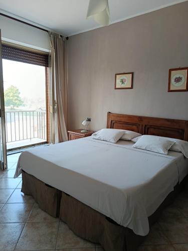 a bedroom with a large bed and a large window at Cascina Longoria in Neive