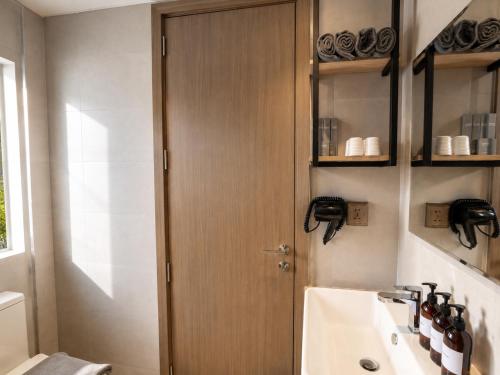 a bathroom with a wooden door next to a sink at One Studio Suite by PSH in Krong Poi Pet