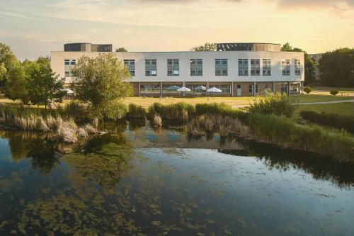 a building with a river in front of it at Hotel Victor Pruszków DeSilva in Pruszków