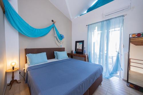 a bedroom with a bed with blue sheets and a window at Michaella's Maissonete at Rafaella Resort in Kokóni