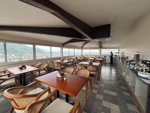 a restaurant with wooden tables and chairs and windows at Hotel De Blossom in Guwahati