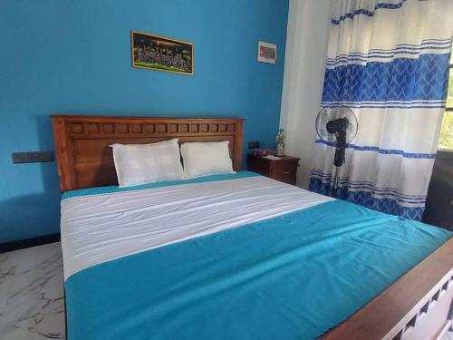 a bedroom with a bed with a blue wall at Ken Homestay Waikkala in Wayikkal