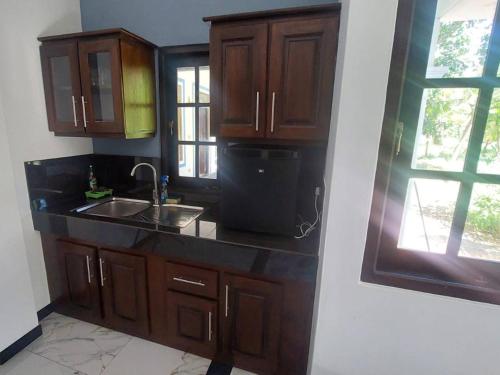 a kitchen with wooden cabinets and a sink and a window at Ken Homestay Waikkala in Wayikkal