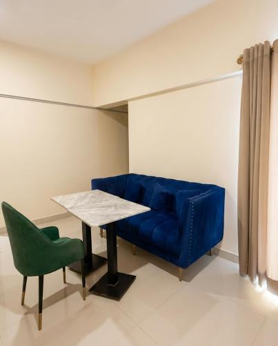 a blue couch and a table and a green chair at Hamsun Apart Hotel Clifton in Karachi