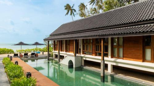 a building with a swimming pool next to the ocean at Siritarar Residence by Elite Havens in Nathon Bay