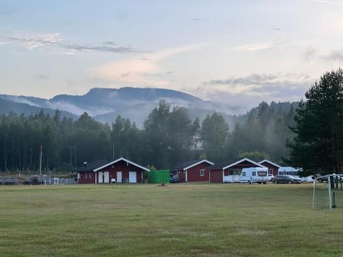 a group of houses in a field with mountains in the background at Sanda Camping og Hytteutleie in Øvrebø