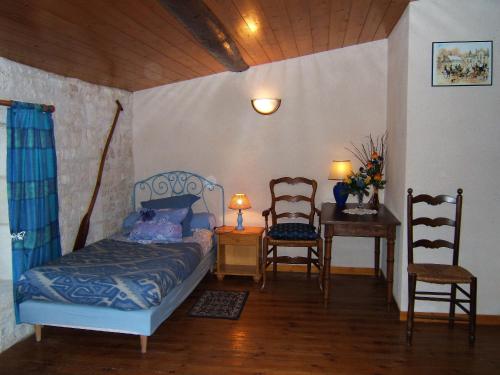 a bedroom with a bed and a table and chairs at Le Logis de bouillé in Bouillé-Courdault