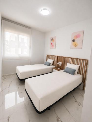 two beds in a room with white walls at Casa Lauri in Orihuela Costa
