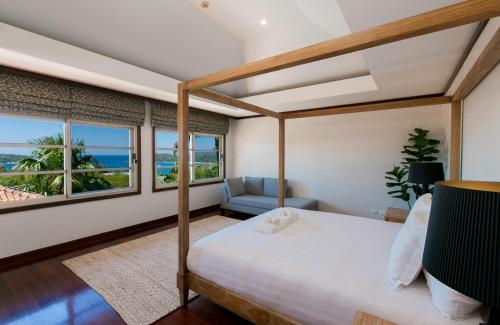 a bedroom with a bed and a chair and windows at Katamanda Aliya Pool & Jacuzzi Villa Kata in Kata Beach