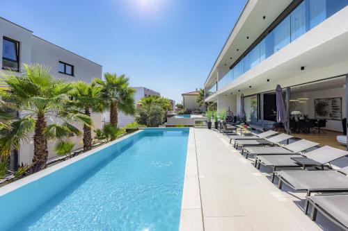 an outdoor swimming pool with lounge chairs and a building at Luxury TABOO Villa & Spa in Medulin for 8 people with heated pool & wellness area in Medulin